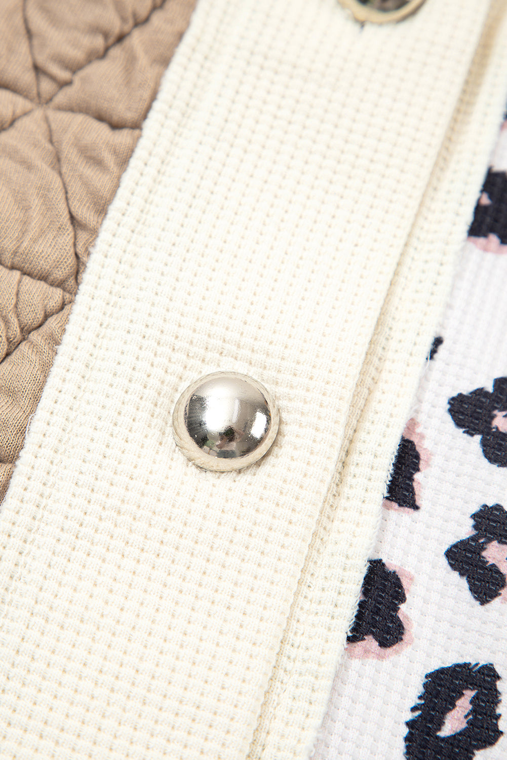 Close-up of a textured fabric surface with a button and a patterned fabric edge.