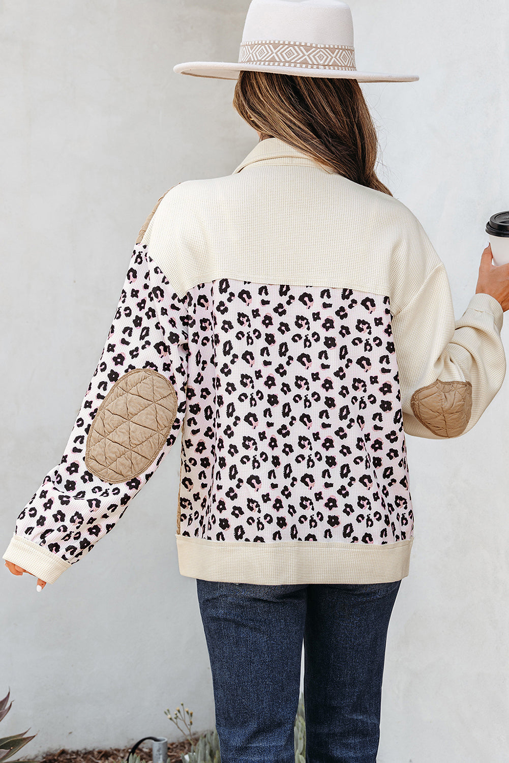 Person wearing a cream jacket with leopard print sleeves against a white background