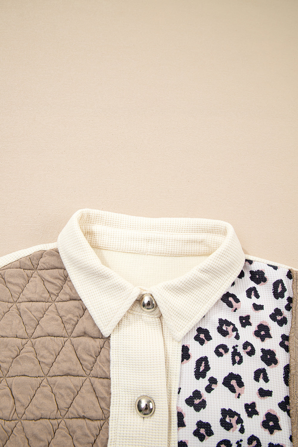 Close-up of a quilted vest with a white collar and leopard print pattern on a beige background