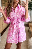 Woman wearing a pink and white patterned dress indoors.