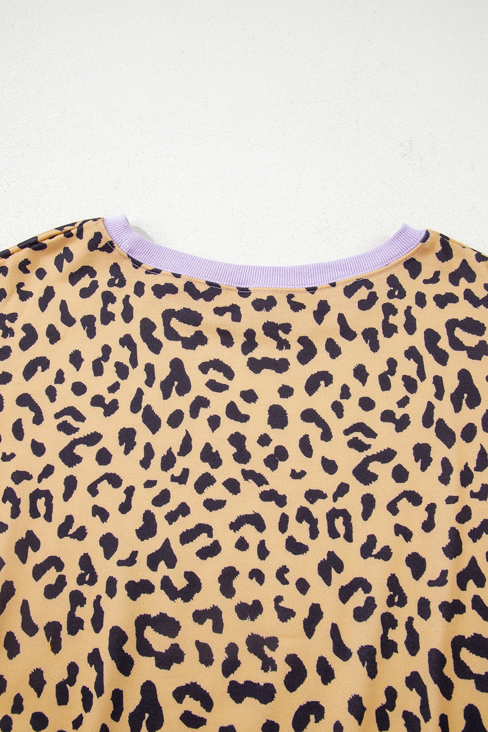 Close-up of a leopard print garment with a light purple trim on a white background
