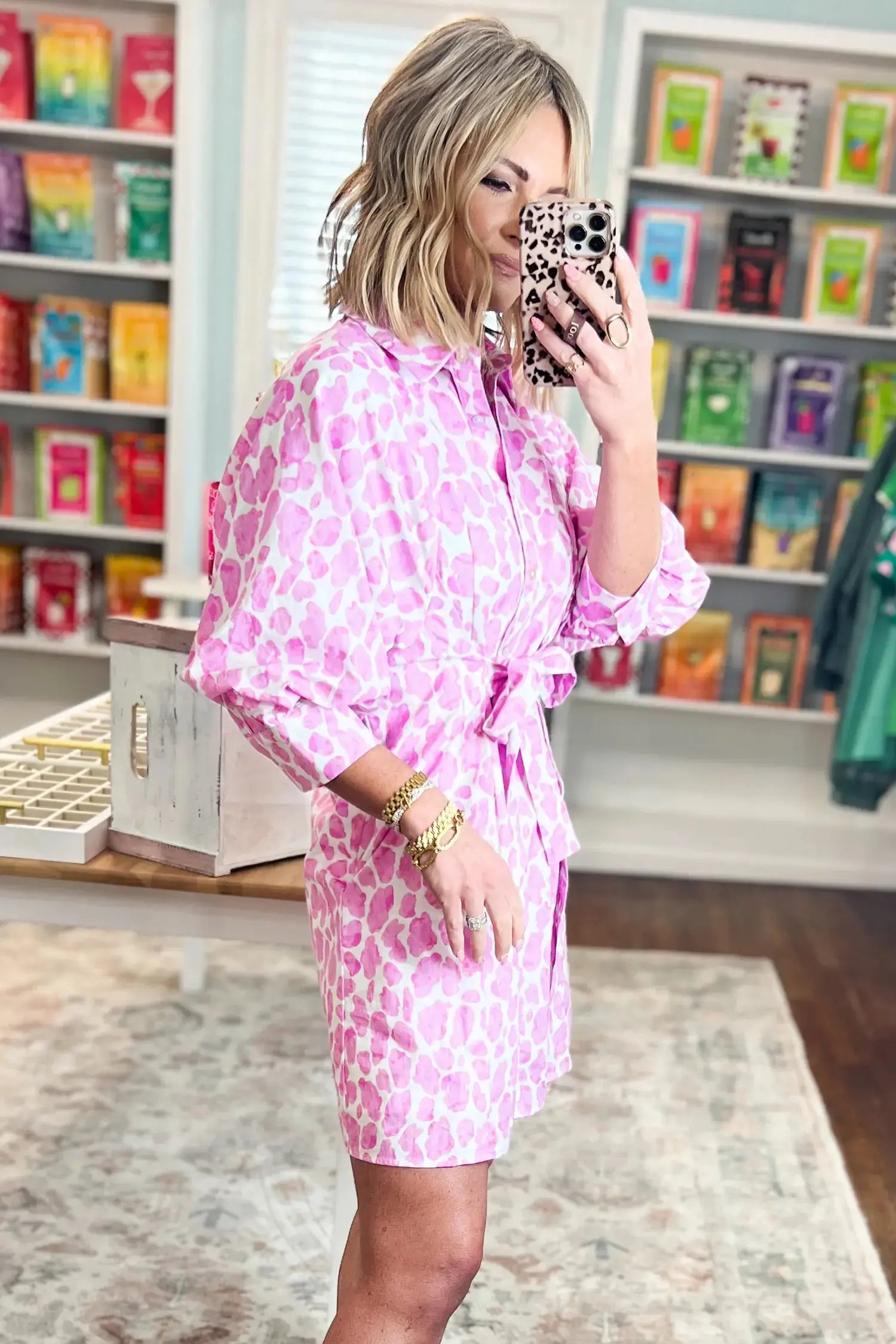 Woman in a pink floral dress taking a selfie in a store.