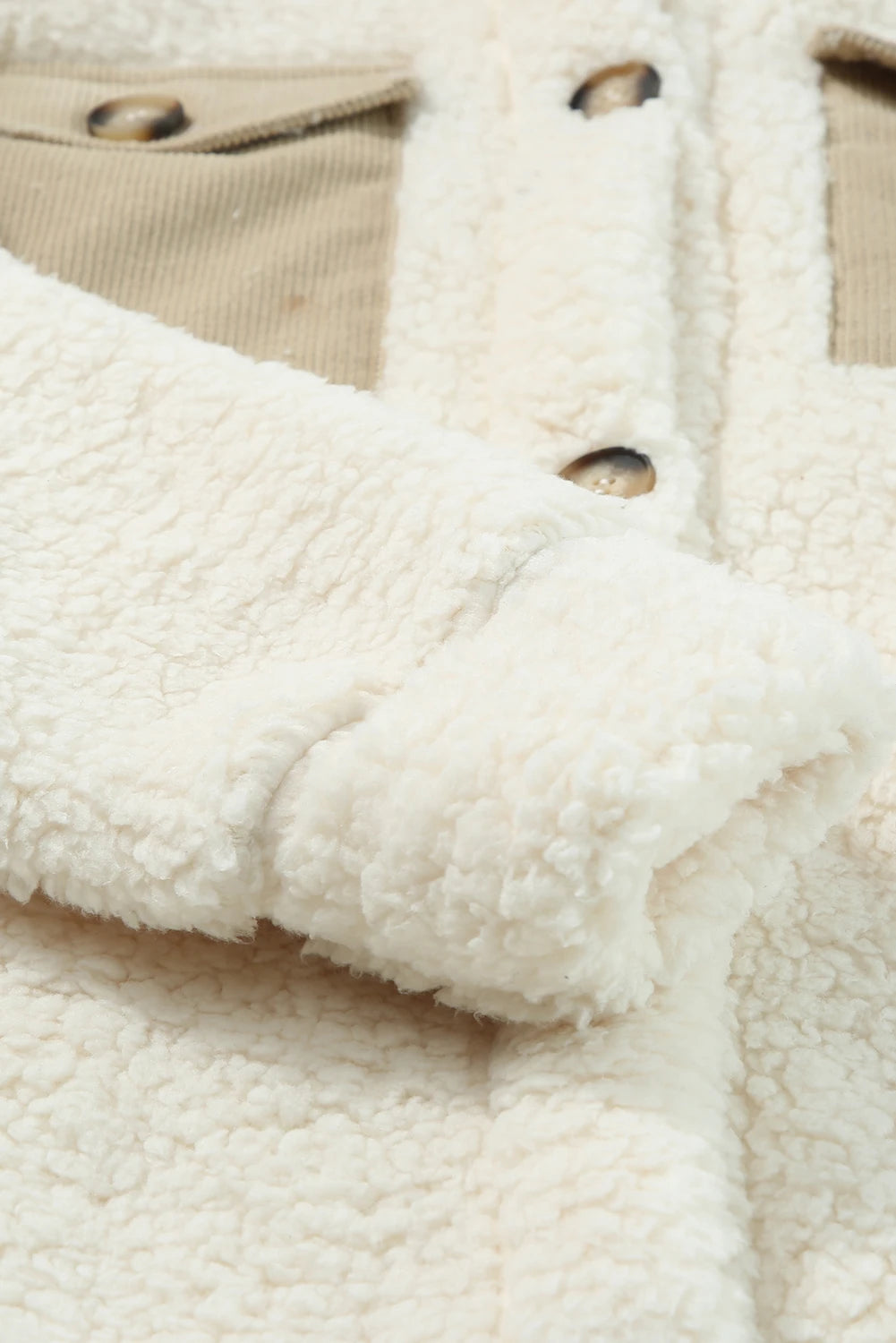 Close-up of a textured fabric with buttons and beige background.