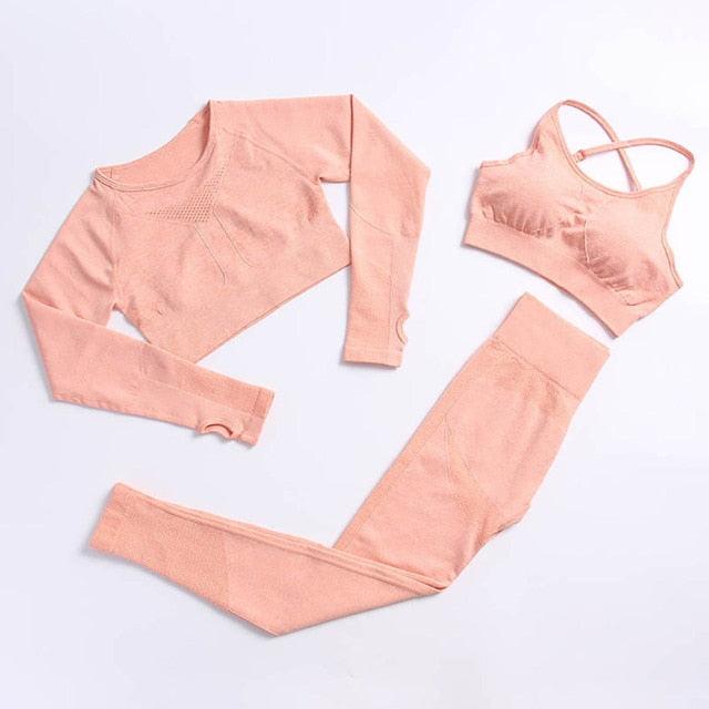 Pink athletic outfit with long-sleeve top, leggings, and sports bra on a light gray background