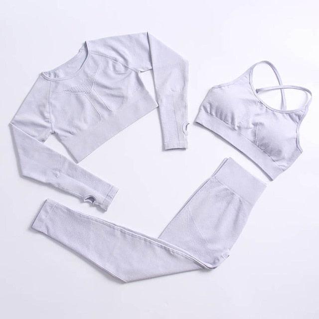 White athletic outfit with long-sleeve top, sports bra, and leggings on a light gray background