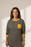 Woman wearing a striped shirt with a yellow pocket on a plain background
