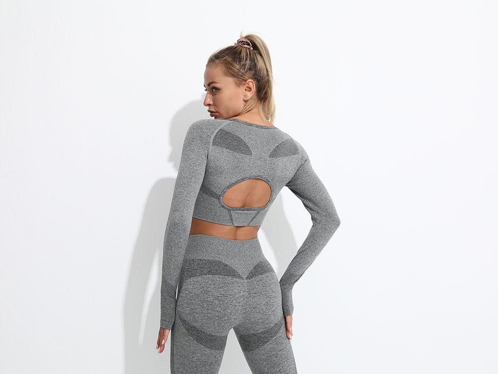 Woman wearing a gray athletic outfit with cut-out design on a white background