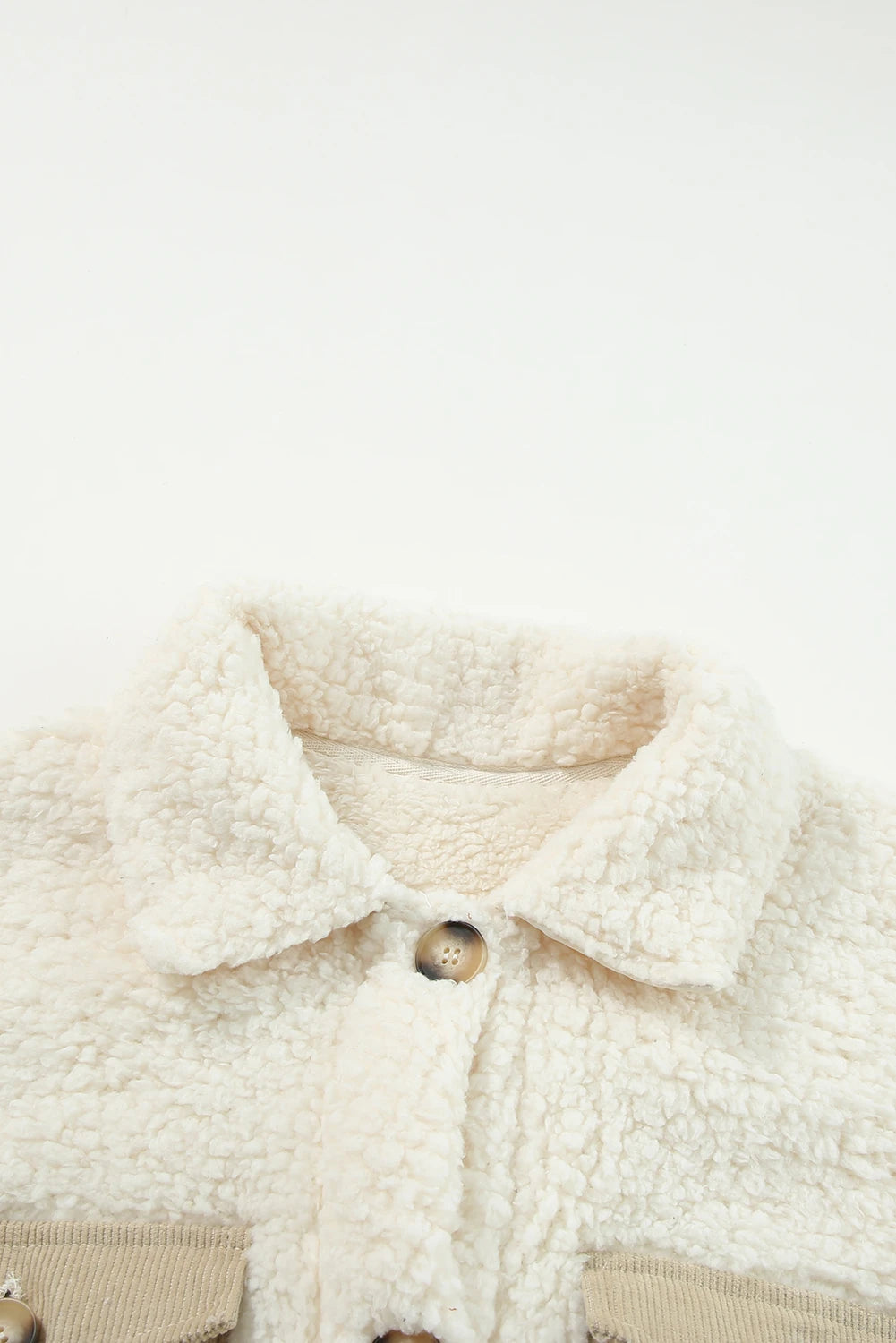 Close-up of a cream-colored sherpa jacket with buttons on a white background.