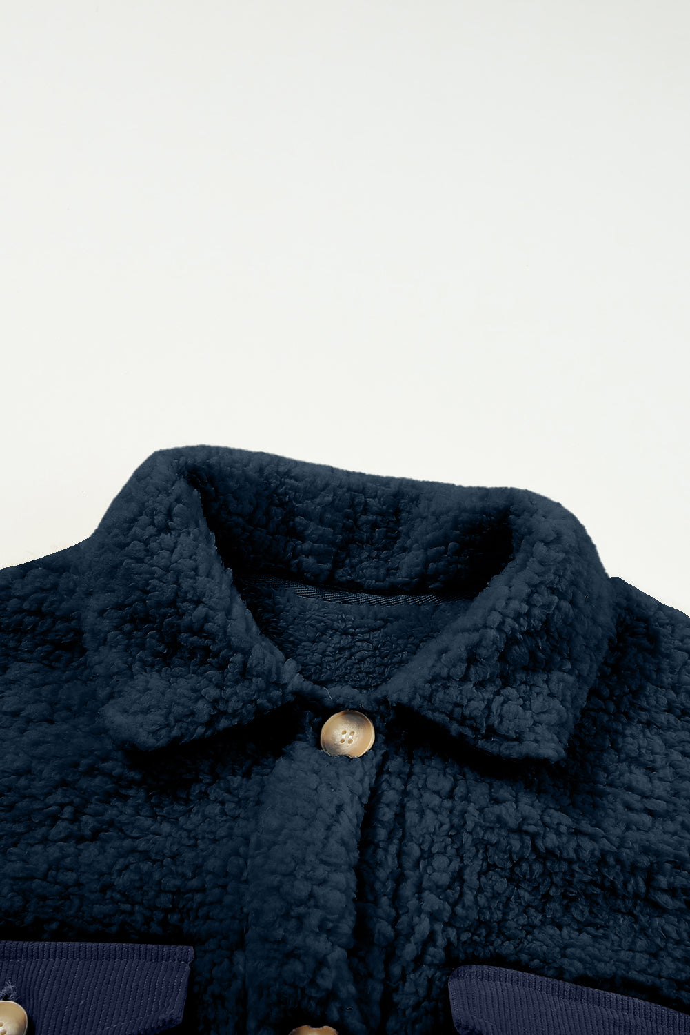 Close-up of a dark blue textured coat with a button on a light gray .background.