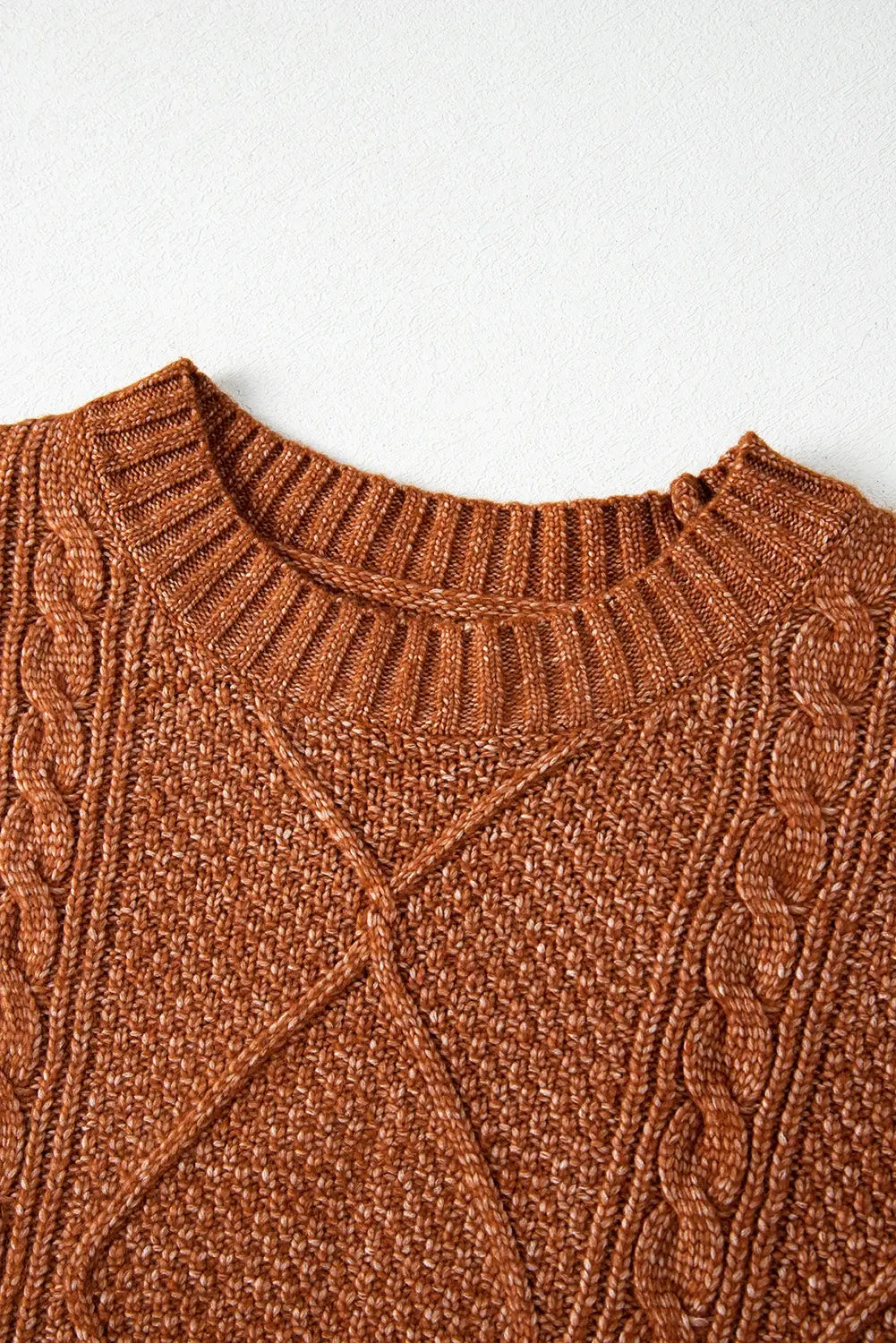 Close-up of a brown cable knit sweater on a white background