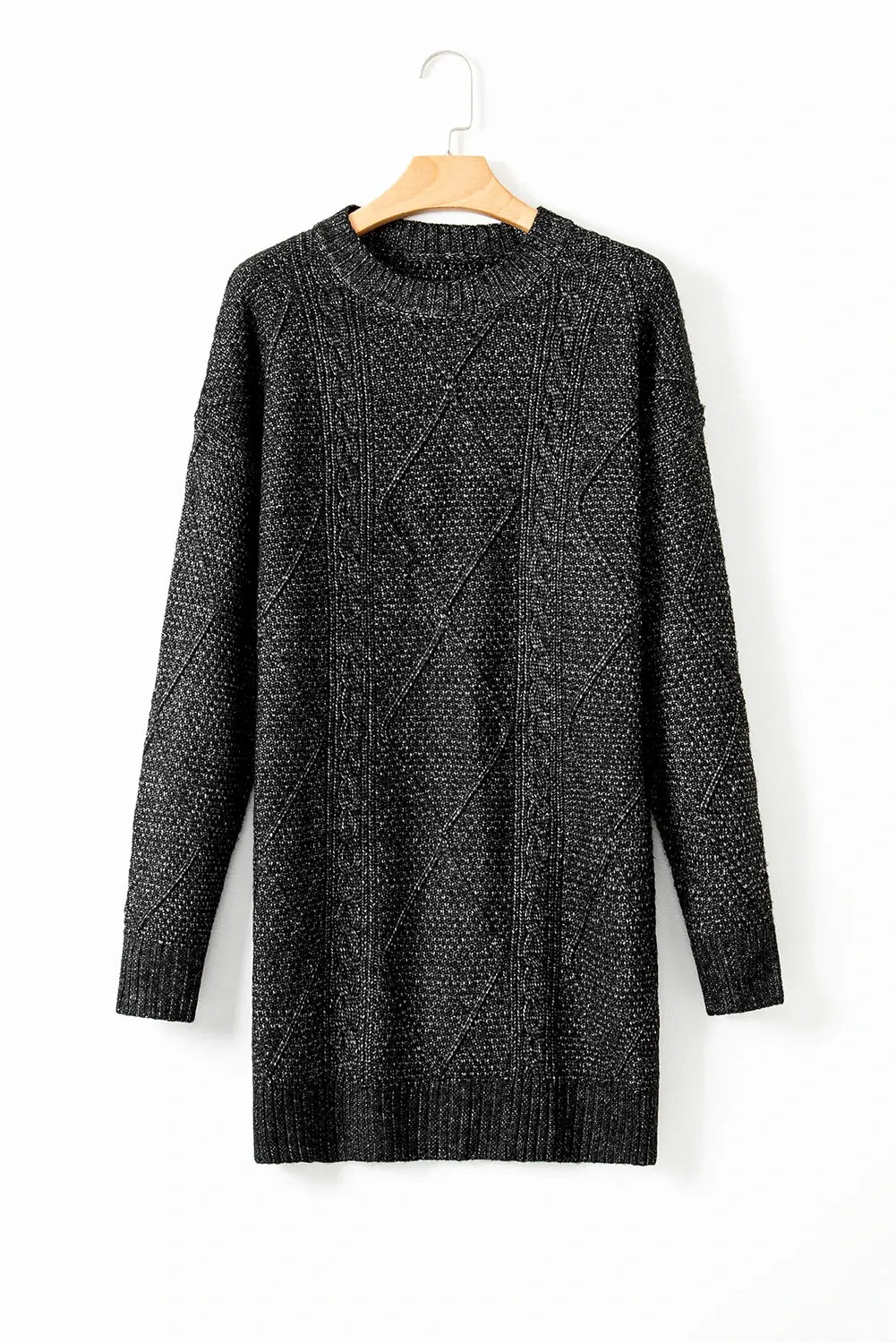 Black cable knit sweater dress on a hanger against a white background