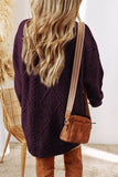 Person wearing a dark purple knitted cardigan with a brown leather bag indoors.