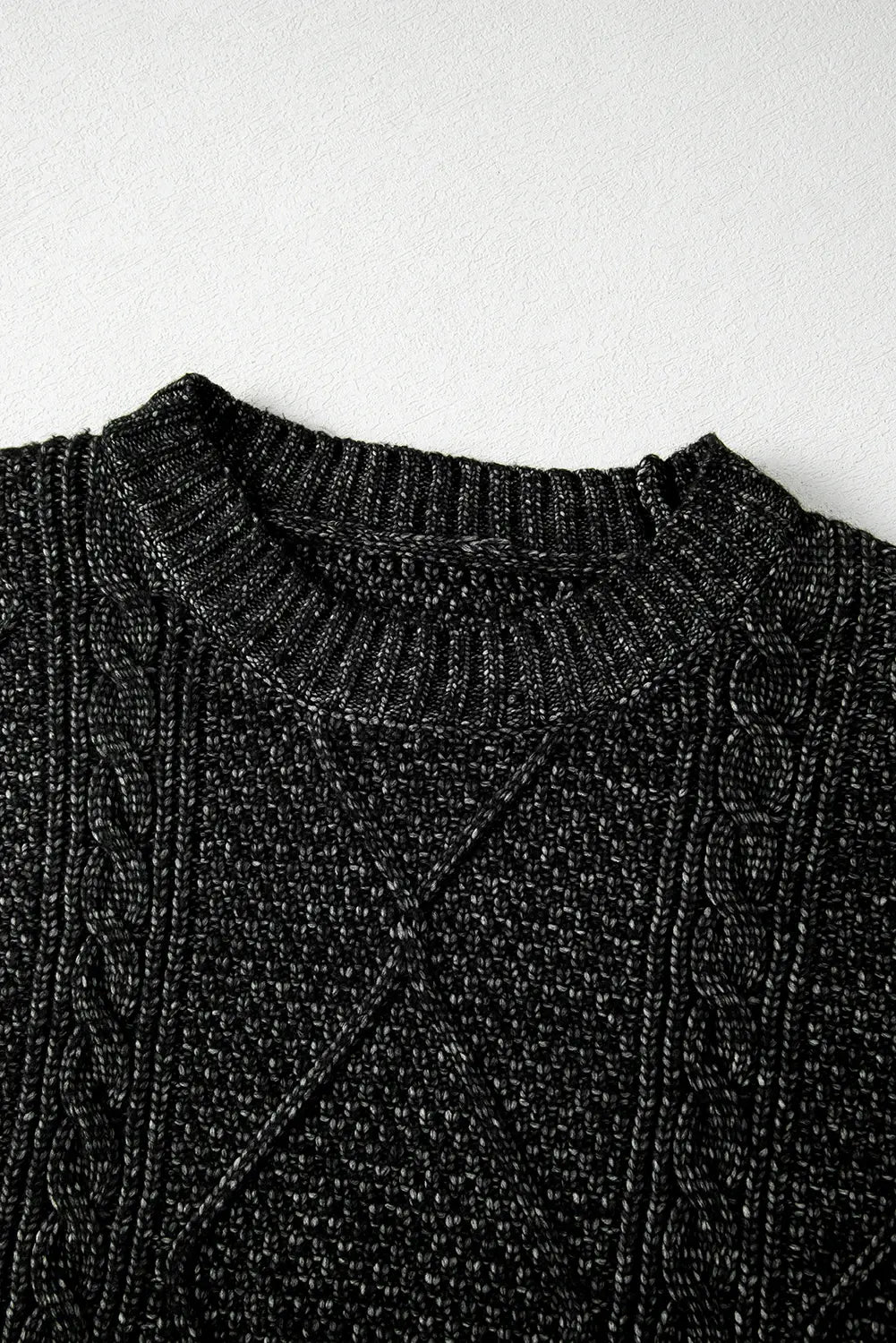 Close-up of a black knit sweater on a white background