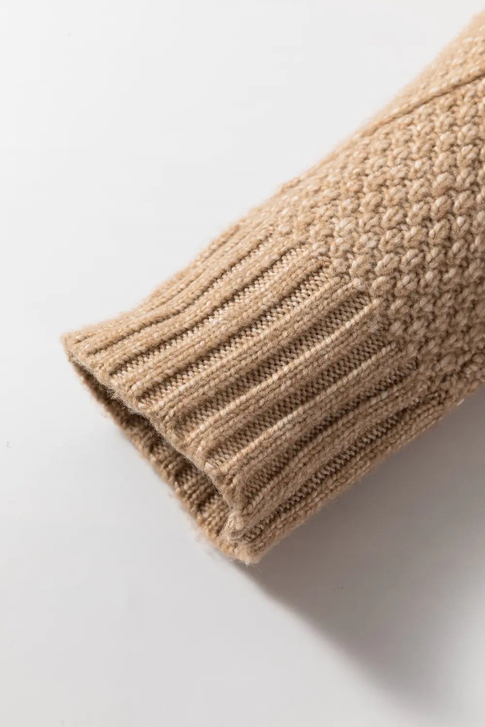 Close-up of a beige knitted sleeve on a light gray background