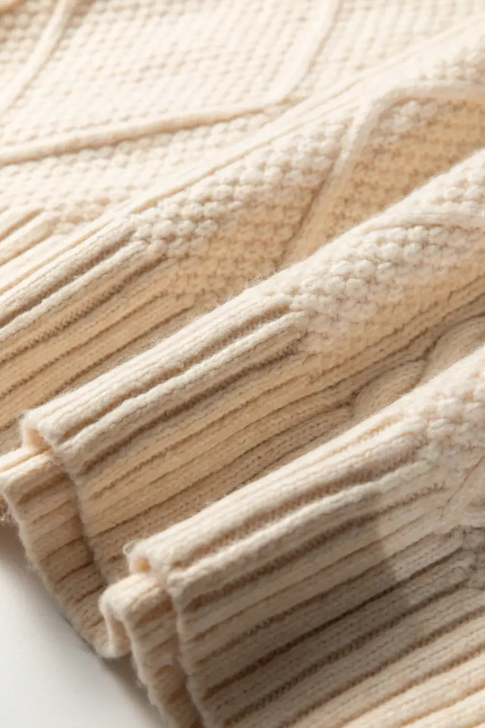 Close-up of a beige knitted blanket with cable pattern