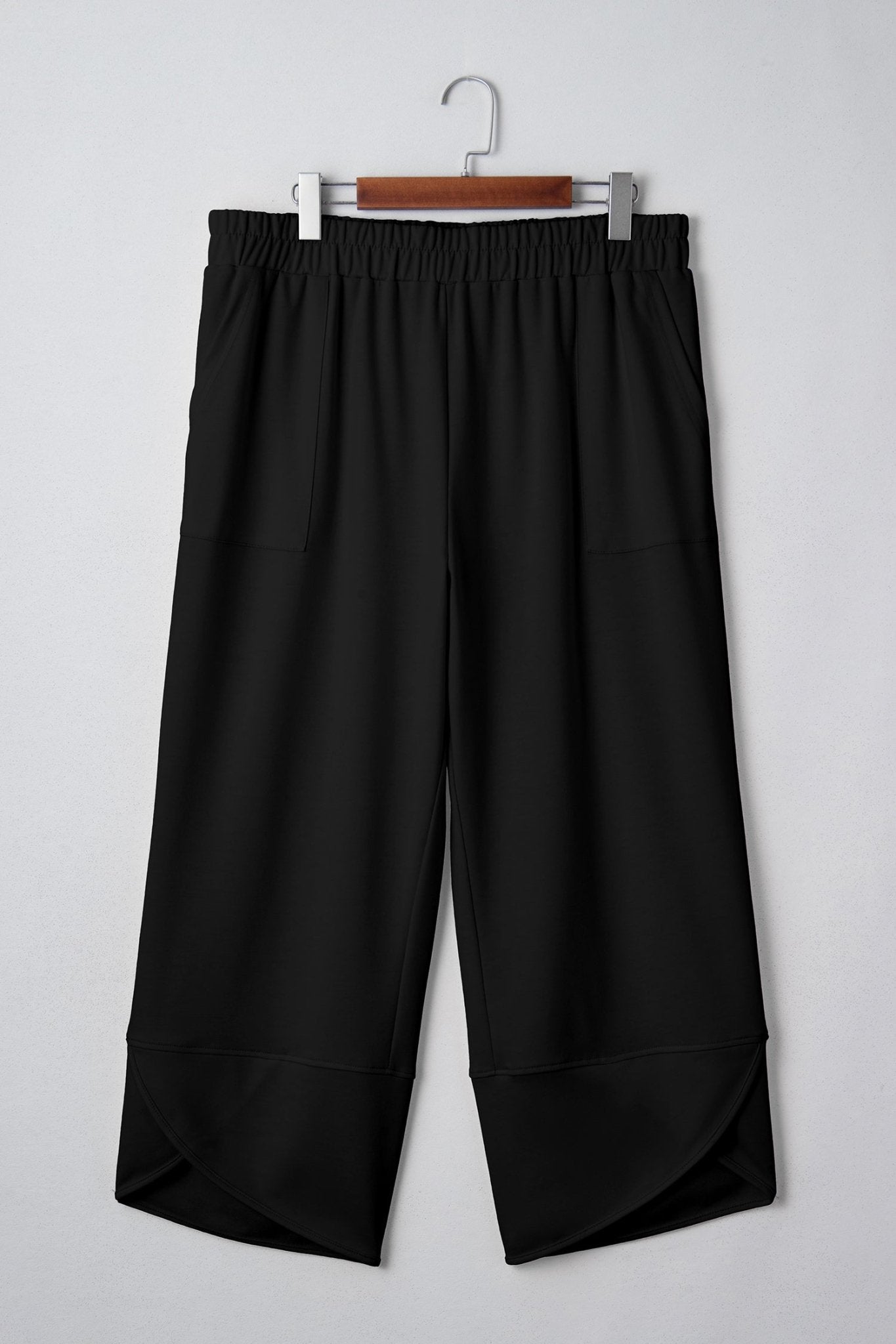 Black wide-leg pants on a hanger against a white background