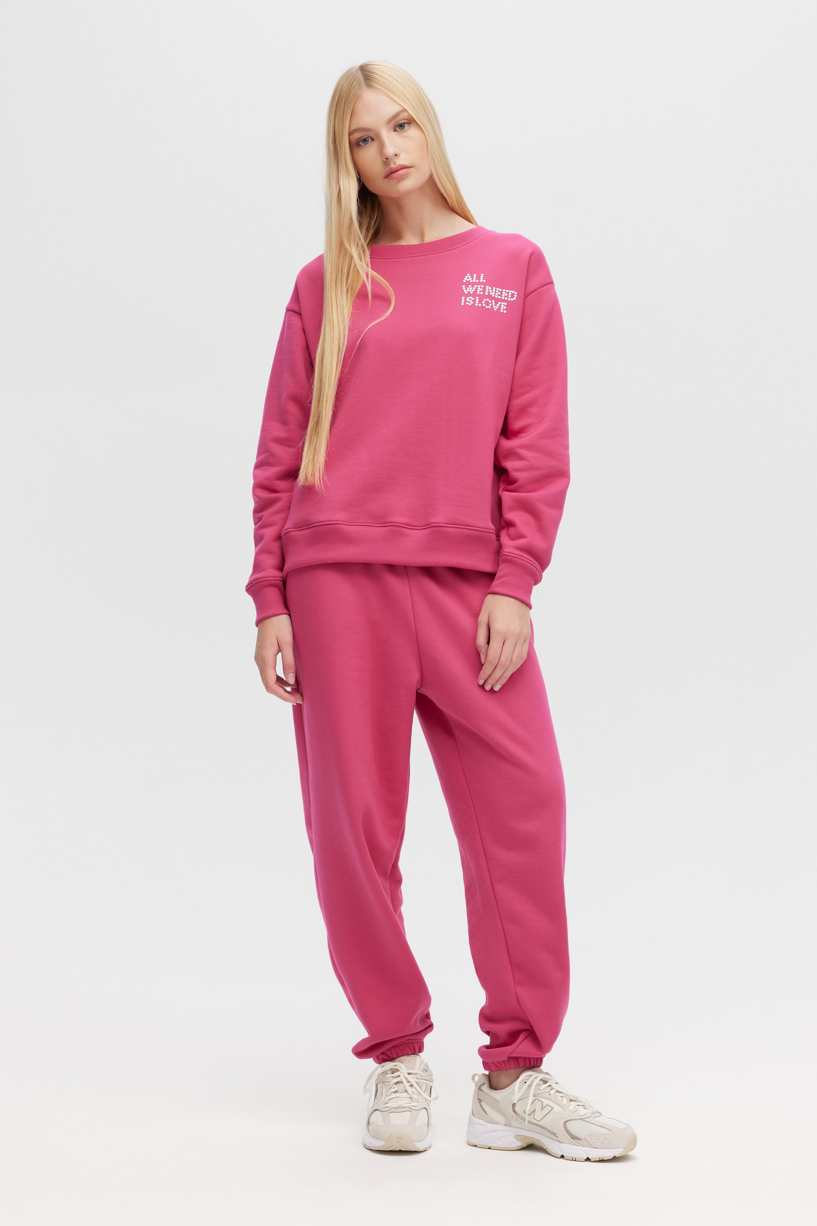 Woman wearing a pink tracksuit with text on a white background