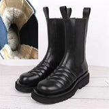Black leather boots with a close-up of the interior lining on a light wooden floor.