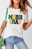 Person wearing a white t-shirt with 'MARDI GRAS' in colorful letters, paired with blue jeans and a green handbag.