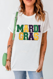 Person wearing a white t-shirt with 'MARDI GRAS' text, holding a green purse against a light background