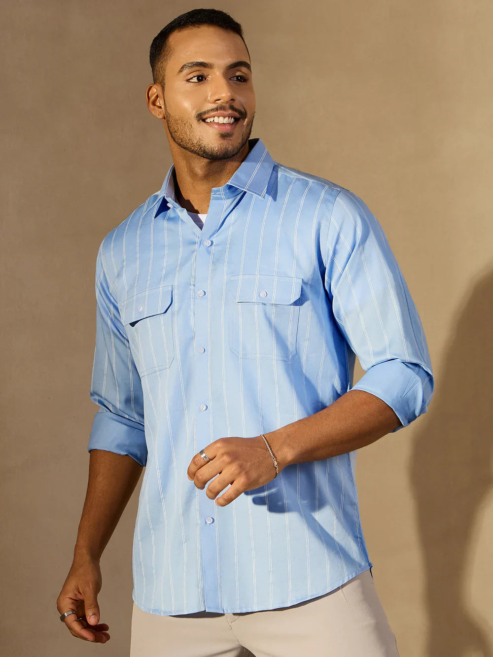 Man wearing a light blue striped shirt against a beige background