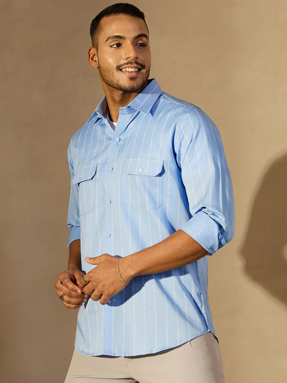 Man wearing a light blue striped shirt against a beige background