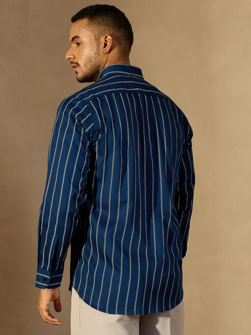 Man wearing a blue pinstripe shirt against a beige background