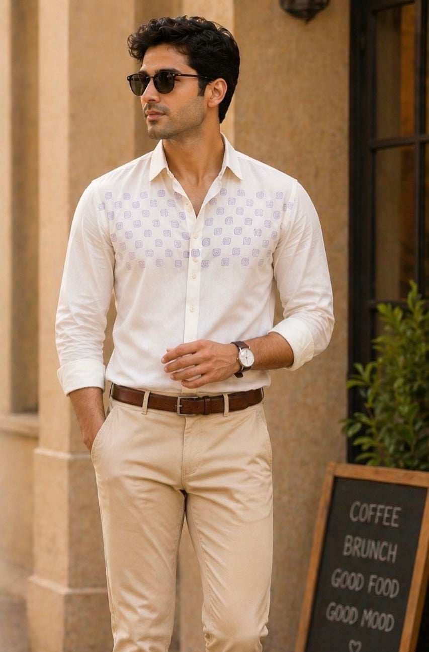 Man wearing a white checkered shirt and beige pants standing outdoors.