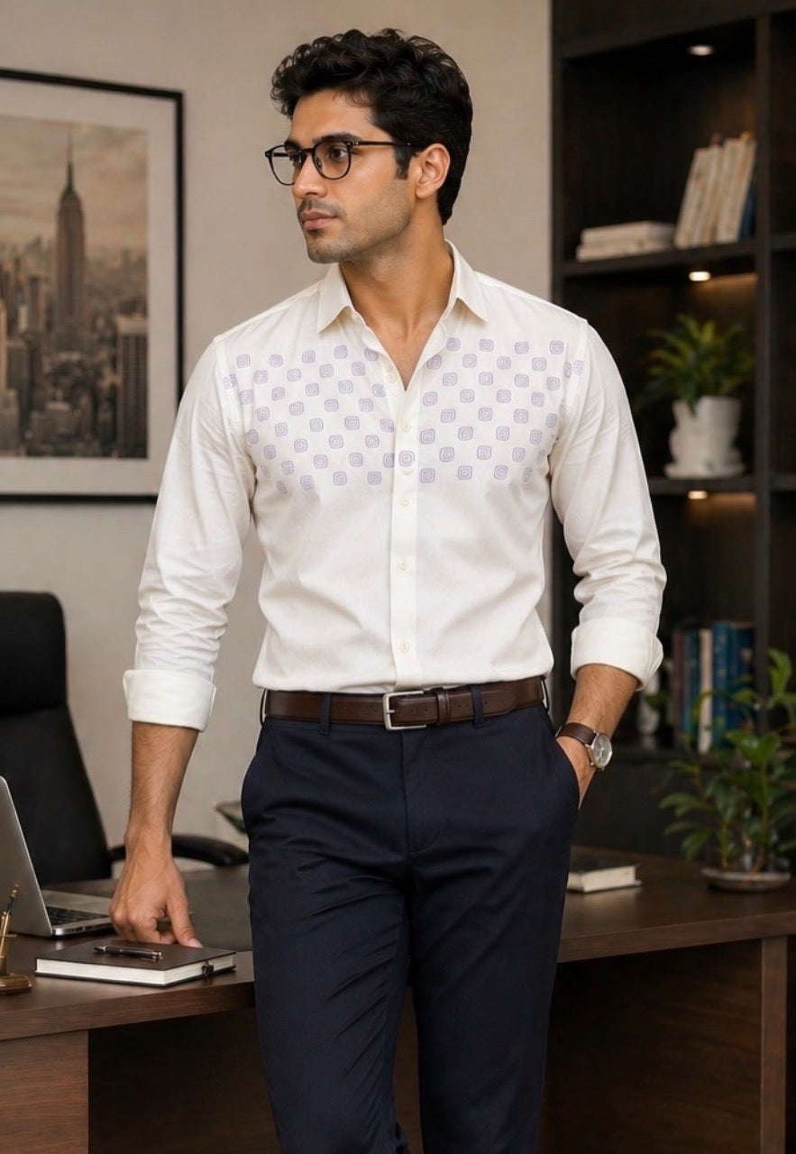 Man in a white patterned shirt and dark pants standing in an office setting.