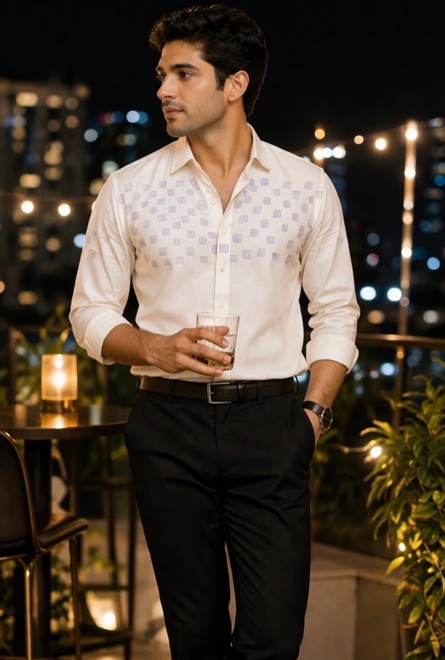 Man in a white shirt and black pants standing on a rooftop with city lights in the background