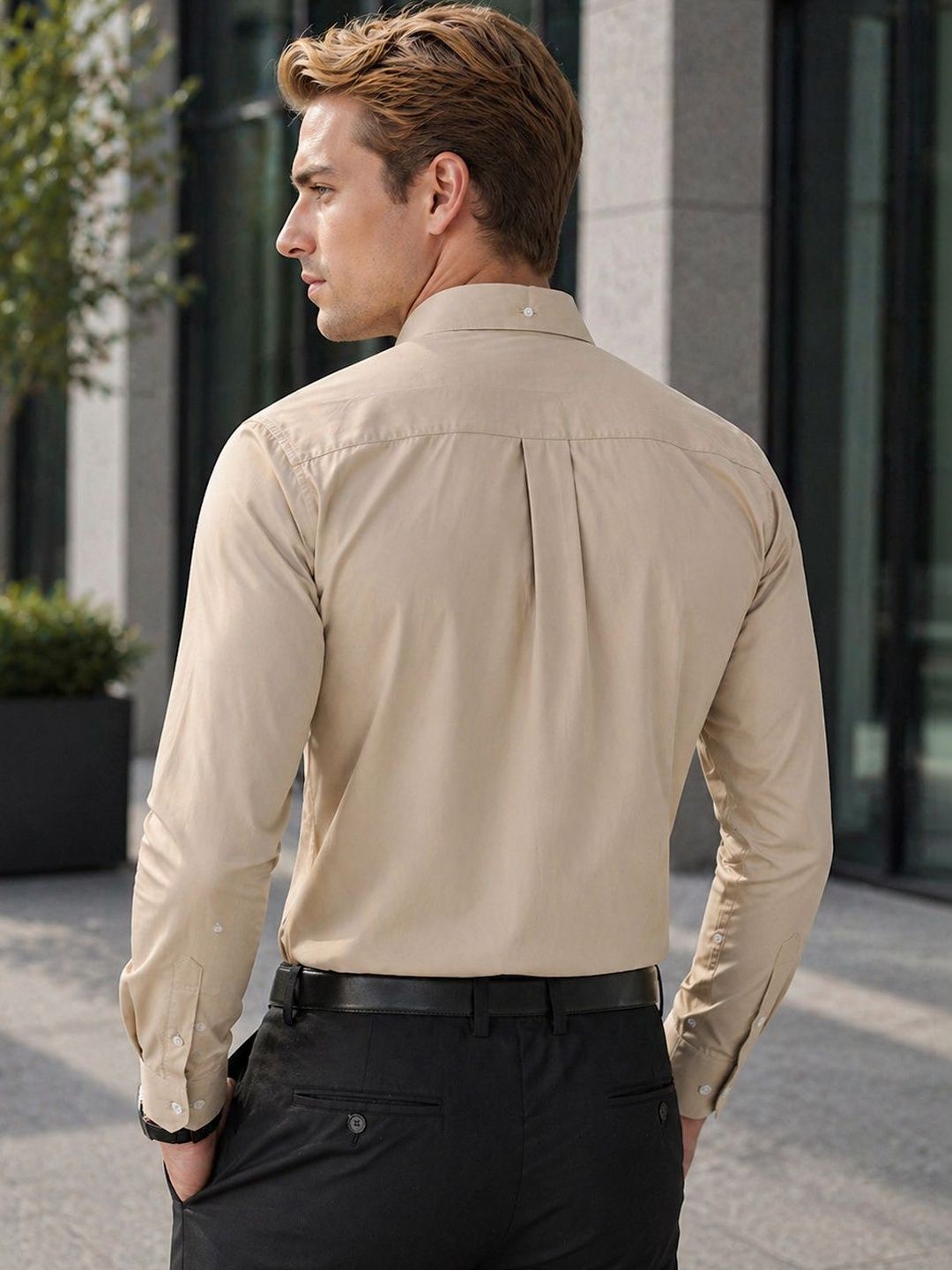 Man wearing a beige shirt and black pants standing outdoors.