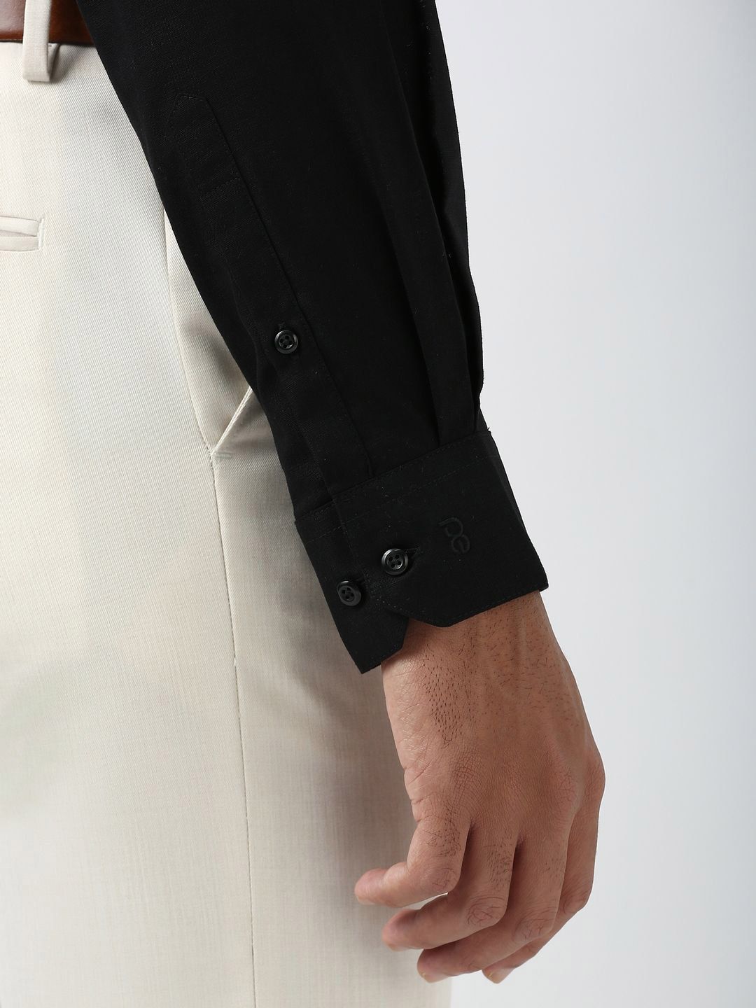 Close-up of a person wearing a black coat with white pants on a light gray background