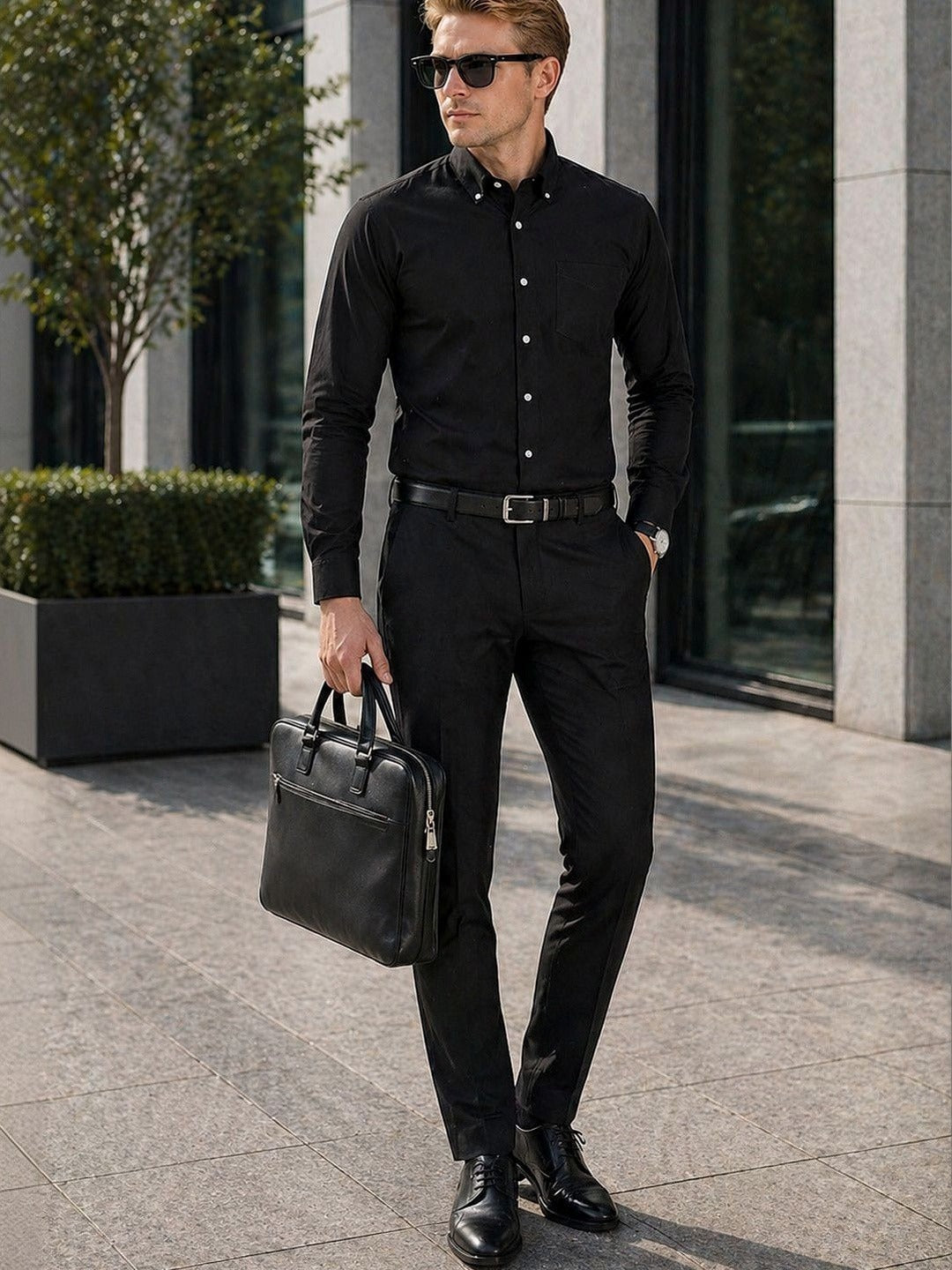 Man in a black outfit holding a briefcase on a city street.