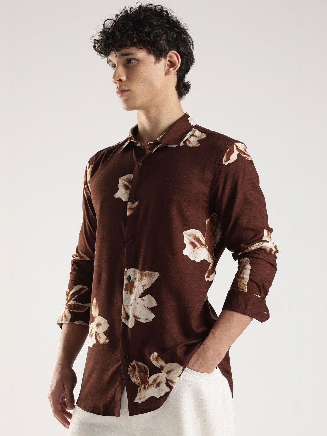 Man wearing a brown floral shirt against a white background