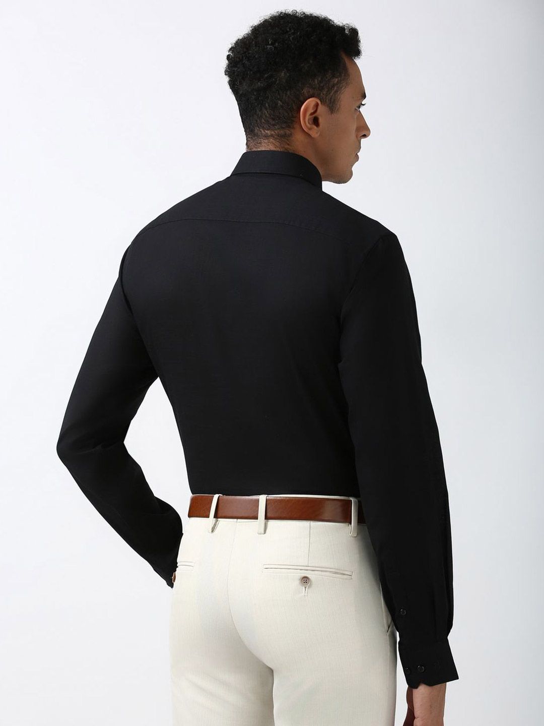 Person wearing a black long-sleeve shirt and white pants on a plain background