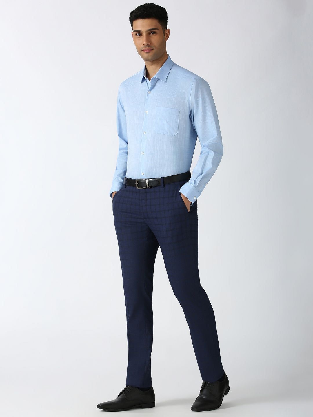 Man wearing a light blue shirt and navy pants on a white background