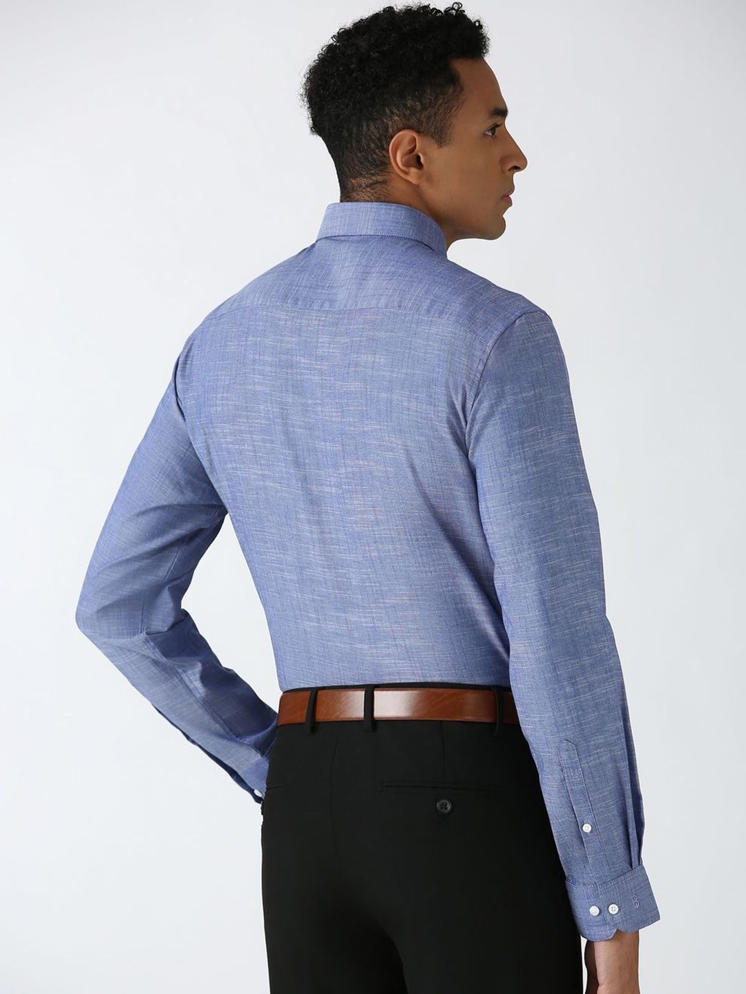 Man wearing a blue checkered shirt and black pants on a white background