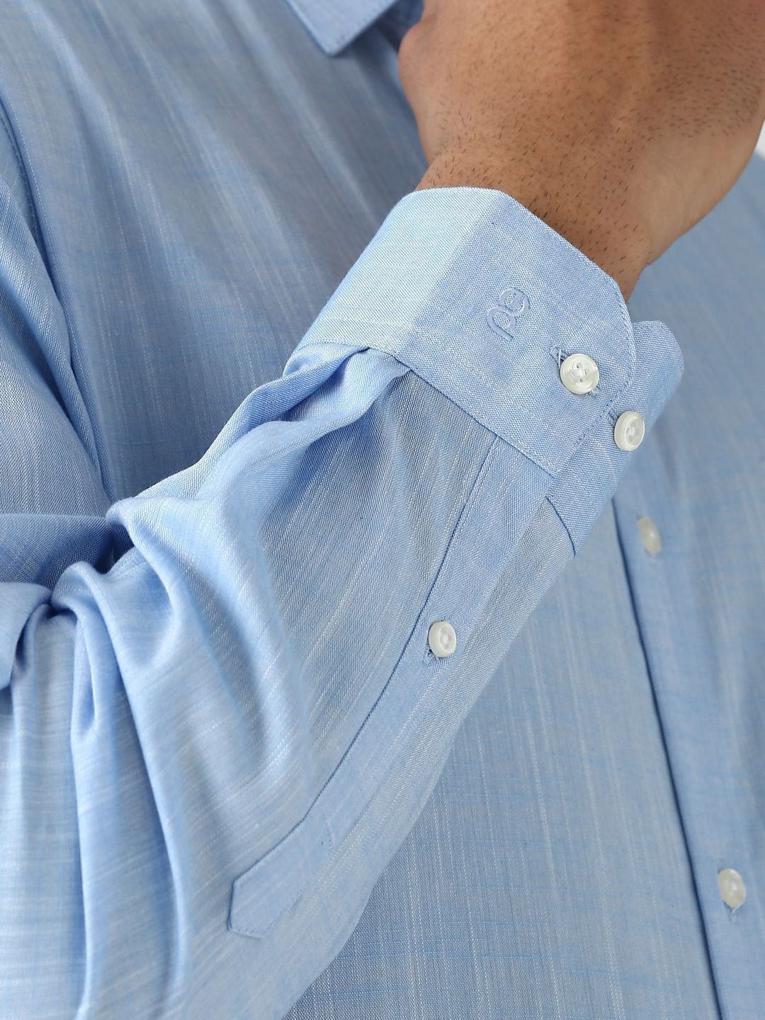 Close-up of a light blue shirt with rolled-up sleeve and visible buttons.