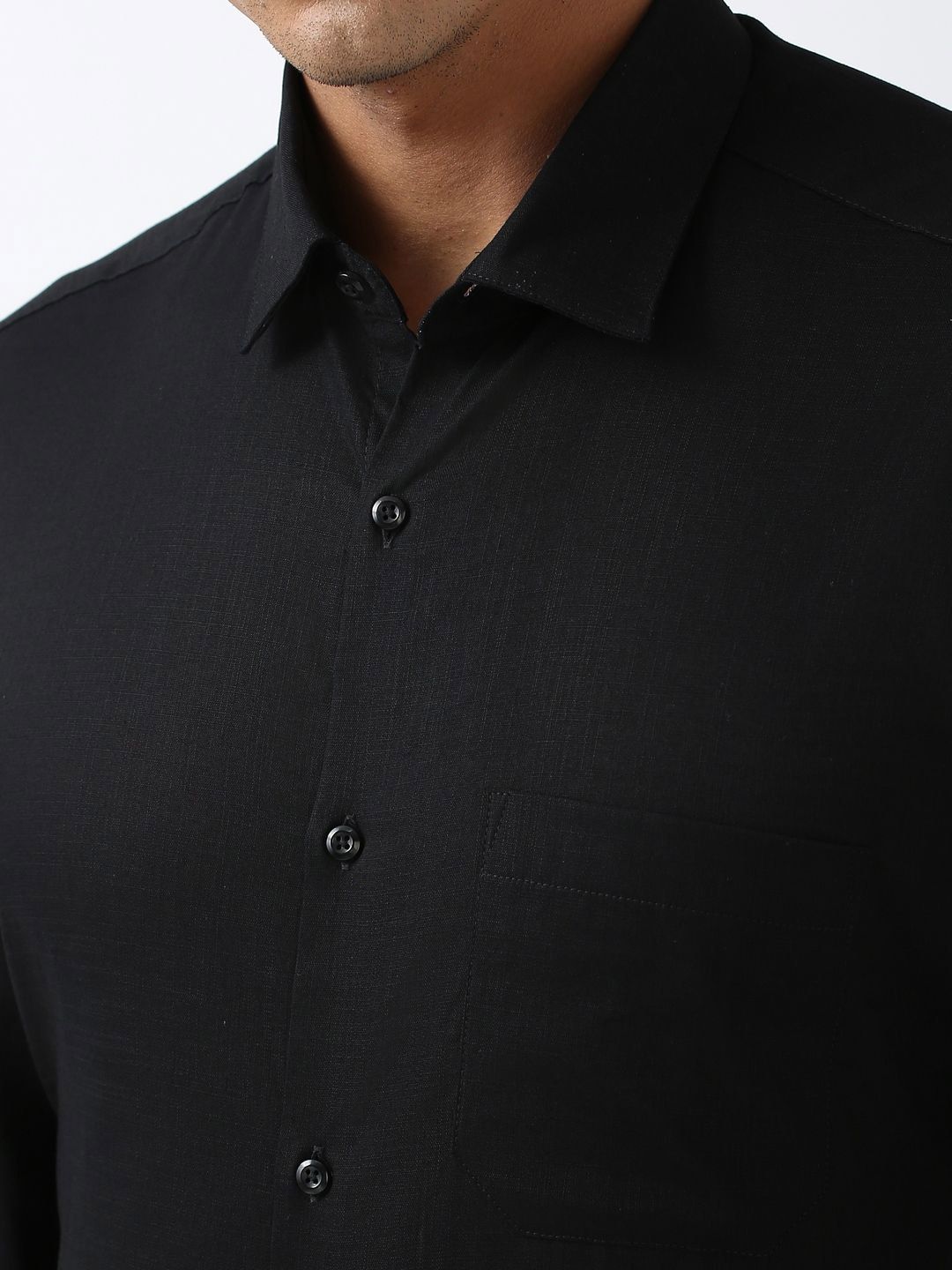 Close-up of a black button-up shirt on a plain background