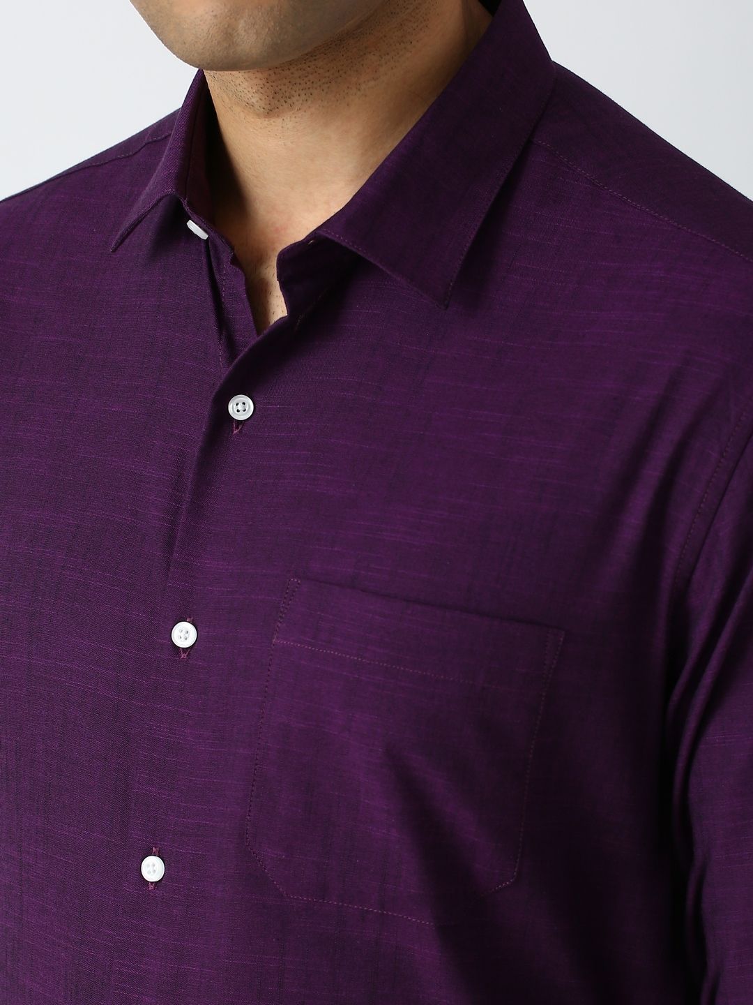 Close-up of a purple shirt with button details on a plain background