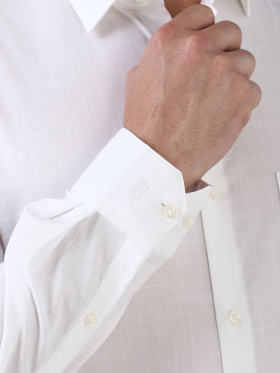 Close-up of a white shirt with rolled-up sleeves and a buttoned cuff.