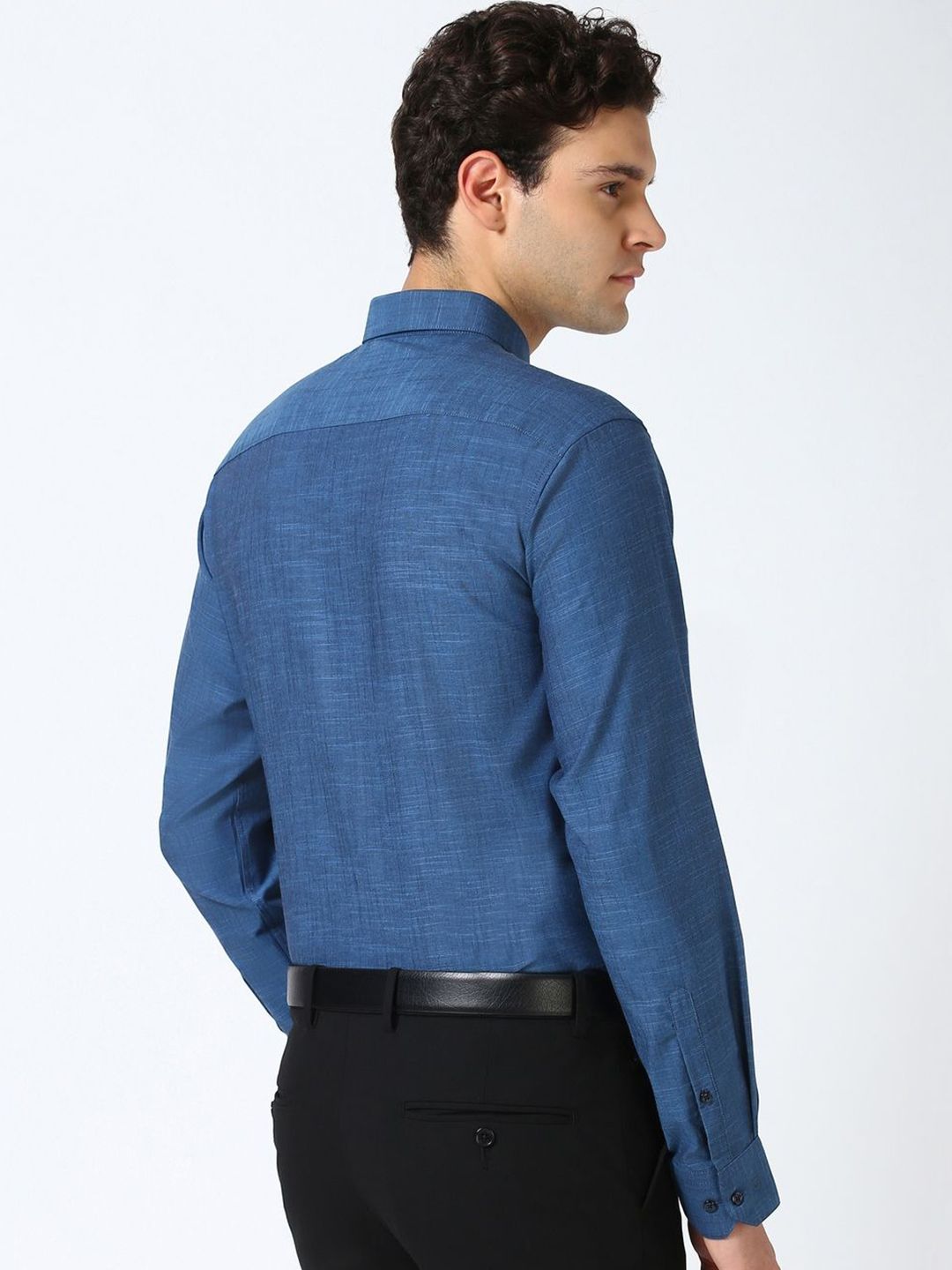 Man wearing a blue shirt and black pants on a white background