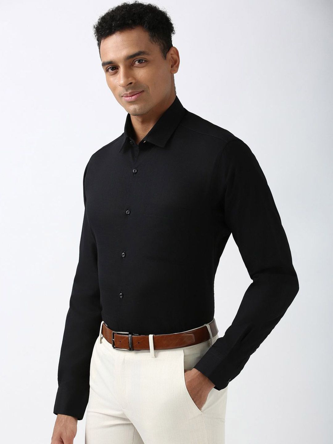 Man wearing a black shirt and white pants on a light gray background
