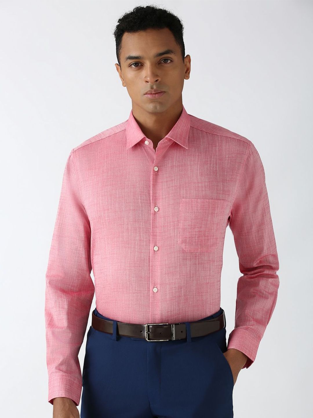 Man wearing a pink checkered shirt and blue pants on a white background