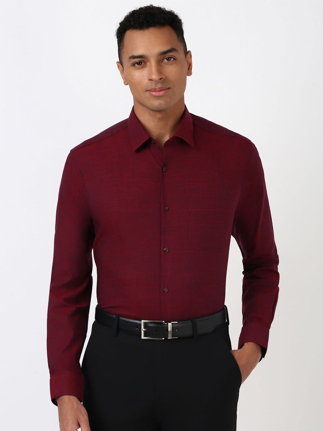 Man wearing a burgundy dress shirt and black pants on a white background