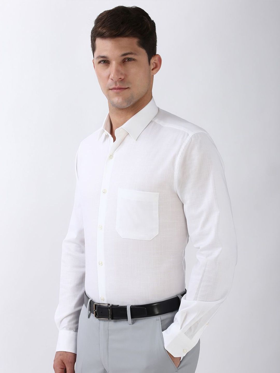 Man wearing a white dress shirt and gray pants against a plain background