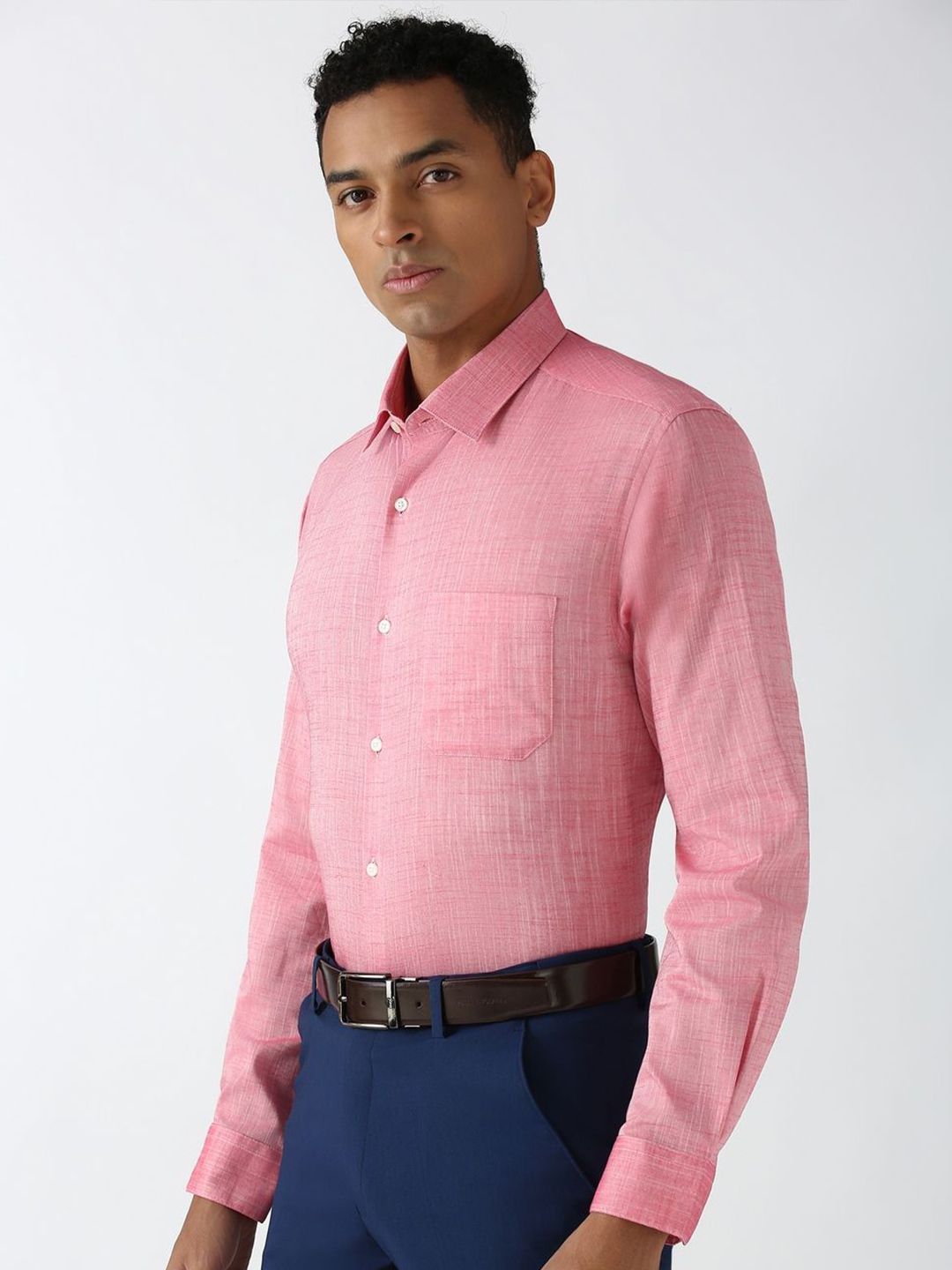 Man wearing a pink checkered shirt and blue pants on a white background