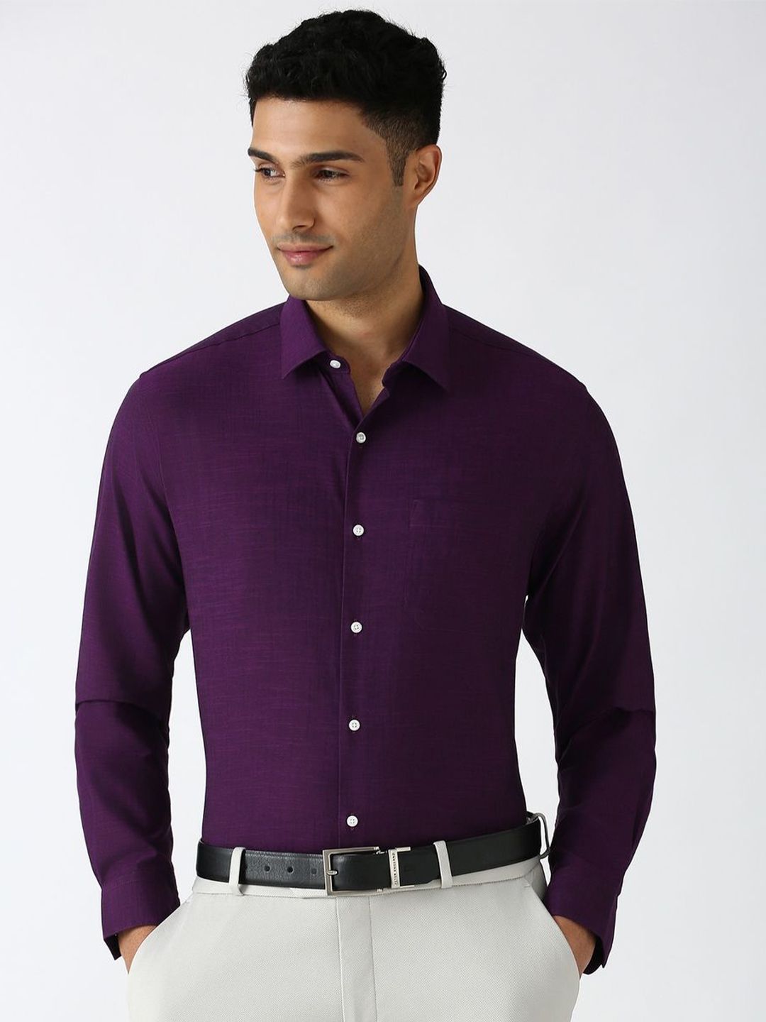 Man wearing a purple dress shirt with white buttons on a plain background