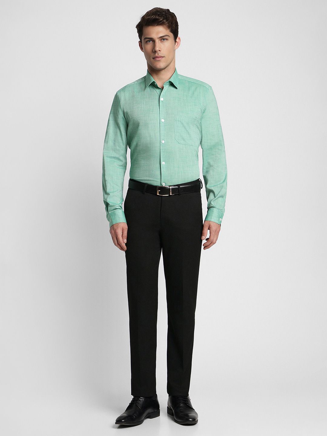Man wearing a green dress shirt and black pants on a white background