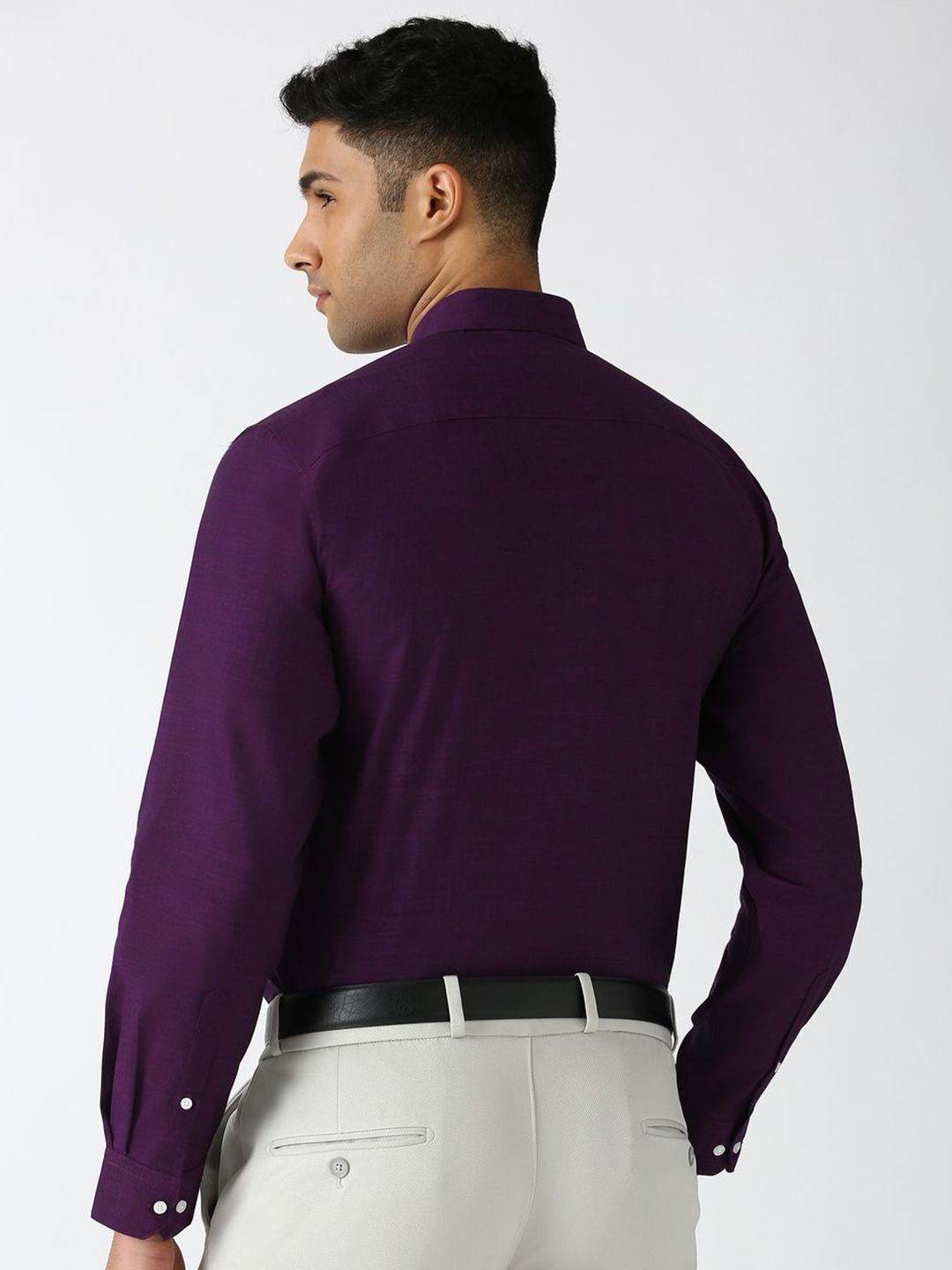 Man wearing a purple dress shirt and light gray pants on a white background